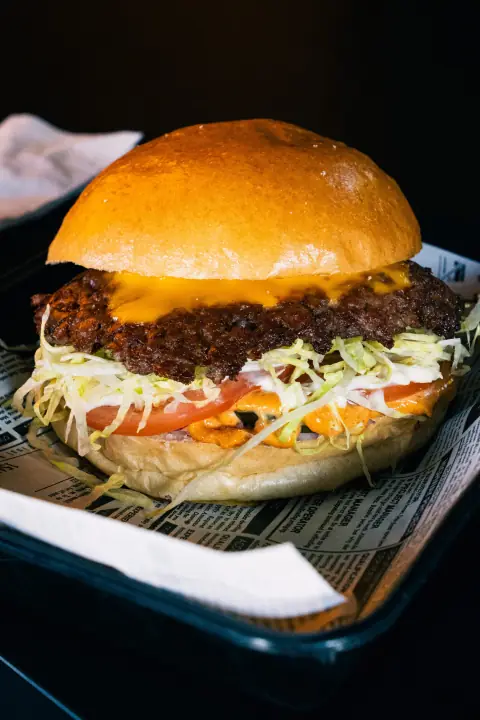 Burger mit Salat und Tomate auf einem Tablett mit Zeitungspapier